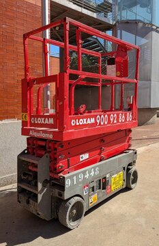 Plataforma elevadora de tijera de color rojo para trabajos en altura con barandilla de seguridad y ruedas para transporte, en Madrid, Espa&ntilde;a, 9 de junio de 2026	