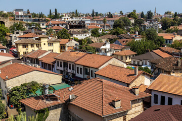 Fototapeta premium High angle view of traditional historic houses with red clay tile roofs in the old town. Kaleiçi, Antalya, Turkey, Mediterranean. Heritage architecture and urban cityscape.