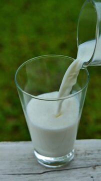 Pouring fresh milk into a glass in bright natural light