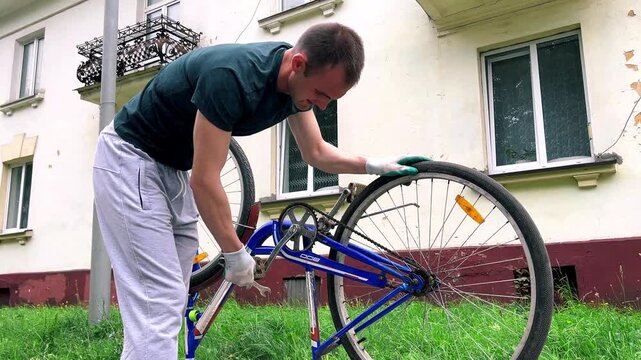 Man repairing bicycle upside down on sidewalk. Checking for hidden defects. DIY mechanical skills in action. Preparing two wheeler for upcoming long journey. Wheel alignment