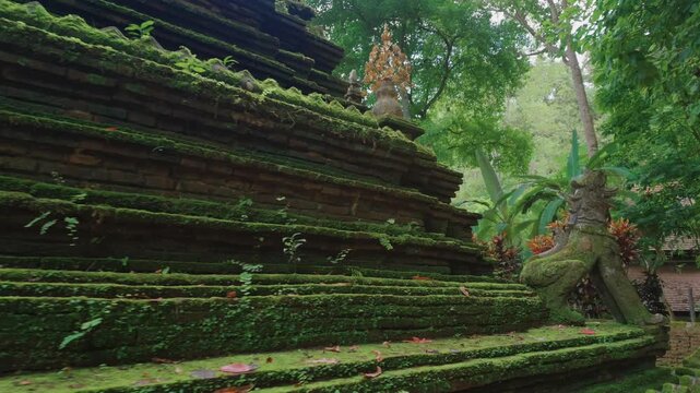 Ancient moss covered Buddhist stupa at tropical forest, Historic Wat Phra Lat temple pagoda with stone guardian sculptures in lush jungle landscape, Chiang Mai, Thailand 4k