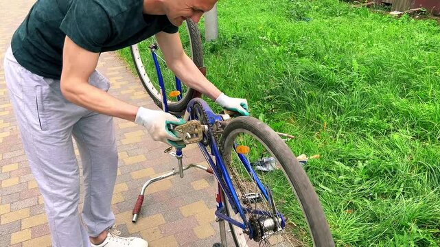 Man flipping bike upside down before house. Checking wheels and chain for damage. Bike repair shows self reliance. Seasonal preparation for summer rides