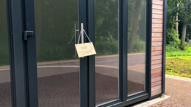 CLOSED sign hanging on small shop door. Small business shutting down due to financial crisis. Local business unable to survive economic pressure
