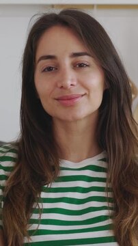 Vertical HD video portrait of young happy Latin American woman smile at camera sitting at kitchen table. People and happiness concept