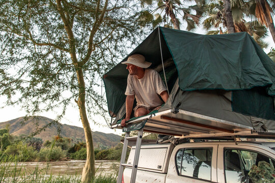 Man camping in rooftop tent near Kunene River Namibia