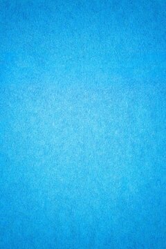Blue paper background texture with gradient. Vintage cerulean cardboard backdrop with dark vignette border.