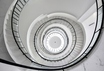 Fototapeta premium Modern white spiral staircase interior design with bright natural light