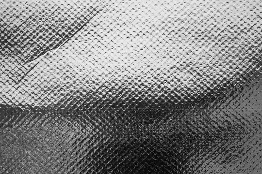 Silver foil texture background with embossed diamond pattern and shiny metallic surface reflection