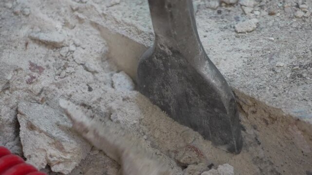 Pneumatic hammer breaking concrete flooring during renovation work. Close-up static shot.