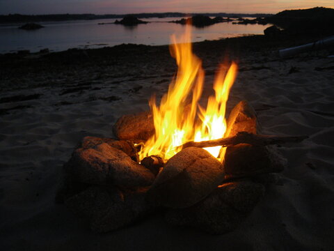 Feu de camp sur le sable d'une &icirc;le en Bretagne (France), mer et c&ocirc;te en arri&egrave;re-plan