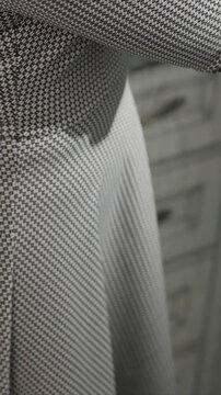 Close up of woman arm and torso wearing black white houndstooth patterned fabric. subject moves slightly showing texture detail on clothing material against indoor background with soft