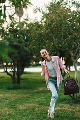Fototapeta premium Smiling student woman running in a park with a backpack, casual daytime scene conveying study life, energy, and outdoor activity. The image captures youthful ambition and everyday campus lifestyle