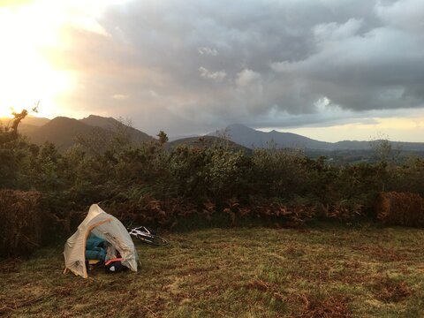 Bivouac automnal dans un champ,  dans les Pyr&eacute;n&eacute;es, lors d'une randonn&eacute;e &agrave; v&eacute;lo, alors que le soleil se couche derri&egrave;re les nuages et les montagnes