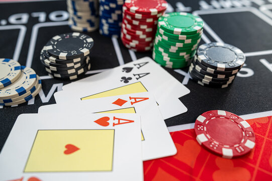 Four Aces Playing Cards Combination with Stacks of Casino Chips on Black Felt Table Surface