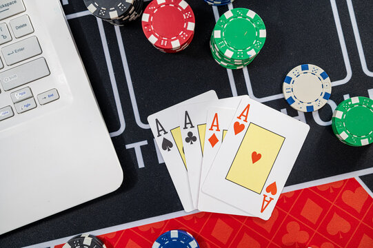 Four Aces Winning Hand with Casino Chips on Laptop Keyboard and Gaming Desk for Online Poker