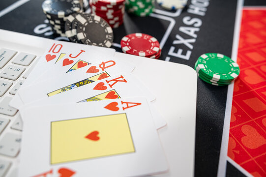 Top View of Royal Flush Hearts Hand with Casino Tokens and Laptop for Virtual Poker Game
