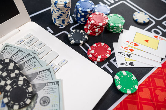 Four Aces Playing Cards with US Dollar Bills Laptop Keyboard and Chips for Online Poker Game