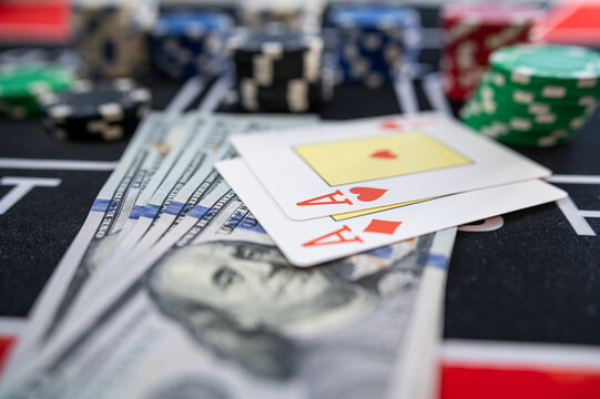 Top View of Hundred Dollar Bills with Pocket Aces Poker Cards and Multi Color Gaming Tokens