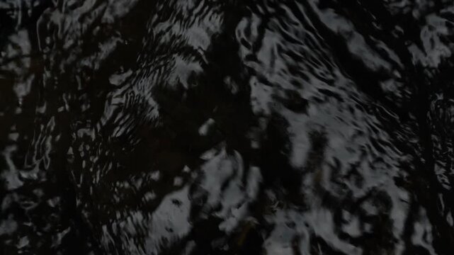 Dark Liquid Water Surface Flowing in Slow Motion Overhead Shot