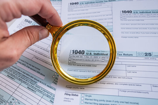 Golden Magnifying Glass on US Tax Form 1040 Papers with Pen for Detailed Audit and IRS Inspection