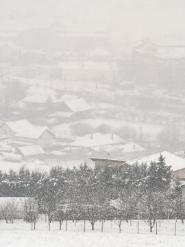 Heavy Snowfall Reduces Visibility Over a Rural Winter Village