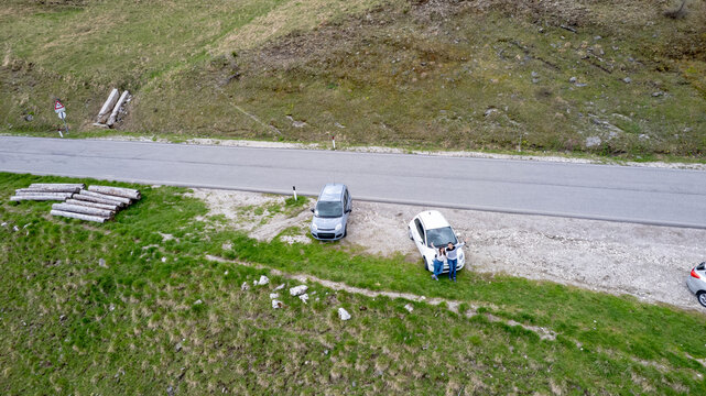 Travelers posing with cars on Passo Giau mountain road