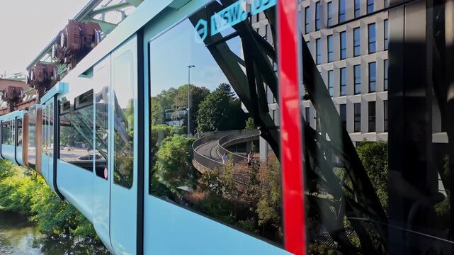 Wuppertal Suspension Railway Traveling Over Urban River and Green Trees on a Sunny Day in Germany