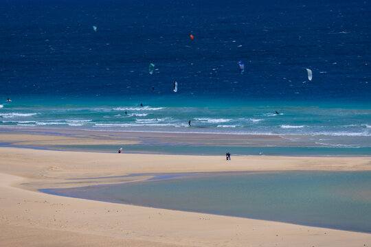 Kitesurfers on a picturesque, windy, sandy Sotavento, Costa Calma, beach with crashing waves, Canary Islands, Fuerteventura, background or wallpaper for your project	