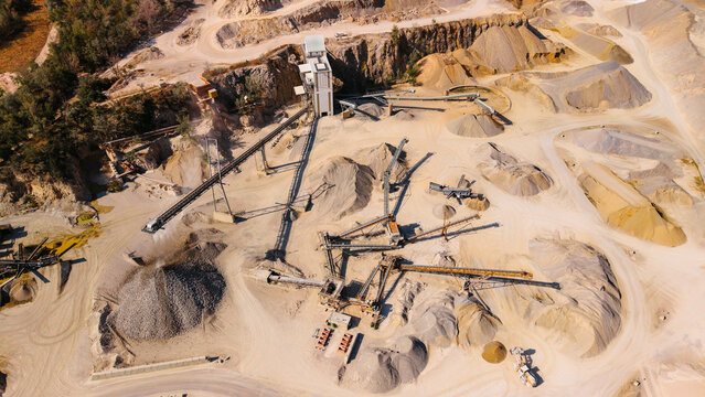 Construction site with machinery and materials in a large quarry. Large machinery works in a quarry where materials are being processed and stored.