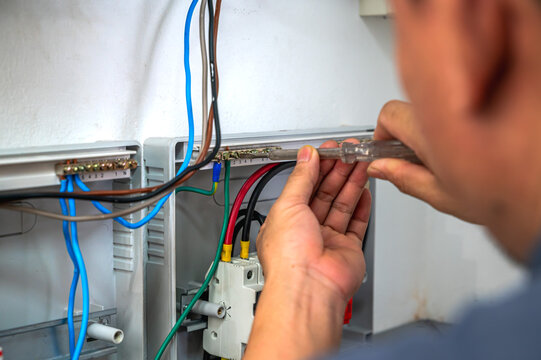 Close up unrecognizable certified electrician using special tool inspecting a wall-mounted solar inverter system box inside a residential home
