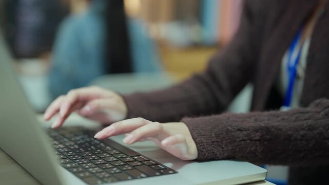 Female Office Worker Entering Financial Data on Laptop Computer