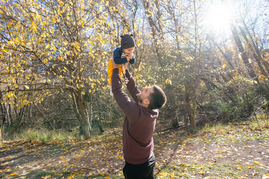 Father playing with baby boy in autumn forest