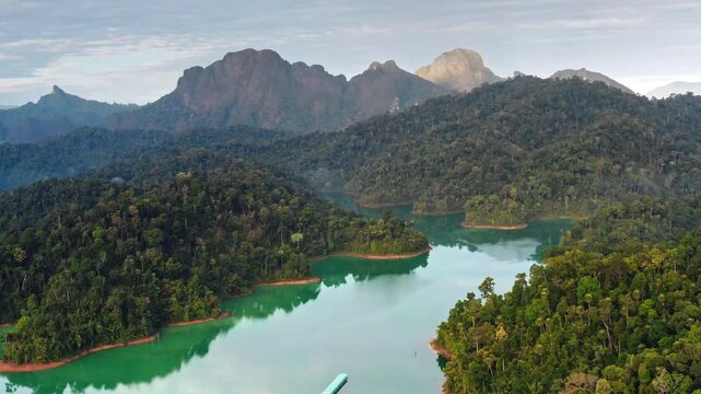 Stunning beauty of Cheow Lan Lake with its emerald green water winding through islands of lush rainforest with dramatic limestone karsts and mountains in Khao Sok National Park, Thailand. Aerial shot