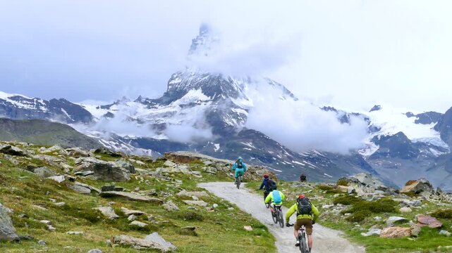 Mountain Bikers Riding Downhill Against the Background of Matterhorn Mountain, Zermatt, Swiss Alps.