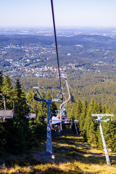Mountain chairlift descends toward panoramic view of Szklarska Poręba surrounded by forested hills. Concept of mountain travel and scenic chairlift transportation through Karkonosze national park.