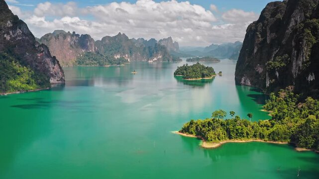 Beautiful Cheow Lan Lake with turquoise water, towering limestone cliffs, and lush tropical islands under a blue sky, creating a breathtaking natural landscape in Khao Sok National Park, Thailand