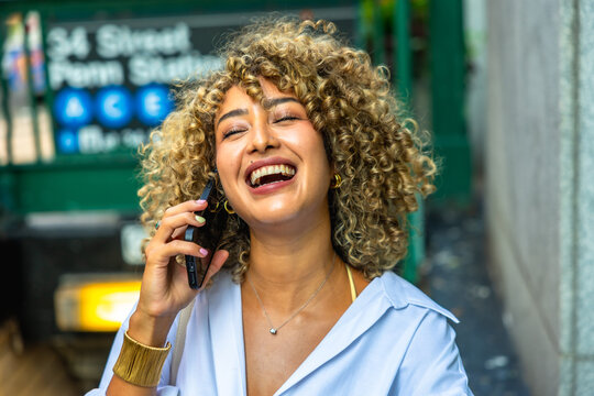 Happy woman laughing using smartphone near subway entrance