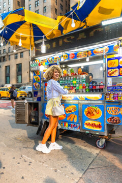 Young woman enjoying street food from a cart in manhattan