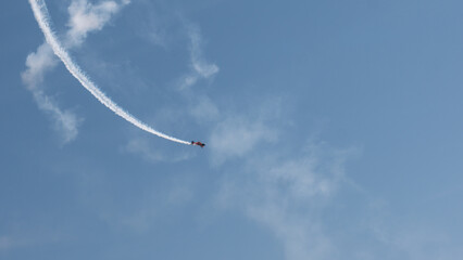 Aerobatic Biplane Trailing a White Smoke Spiral Against a Clear Blue Sky at an Air Show — Precision Flying, Freedom and Adventure Concept © Svetlana
