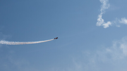 Aerobatic Biplane Trailing a White Smoke Spiral Against a Clear Blue Sky at an Air Show — Precision Flying, Freedom and Adventure Concept © Svetlana