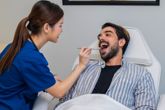 Woman dentist in dental office talking with male patient and preparing for treatment. A dentist talking to man in dentist surgery, a dental check-up.