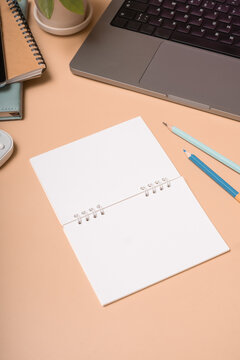 Workspace with blank notebook, tools, and laptop on a desk