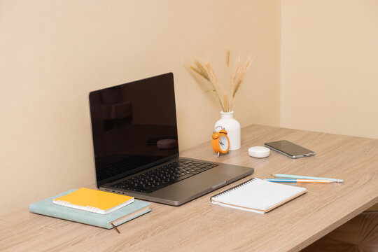 Work desk setup with laptop, notebooks, and phone on a wooden table