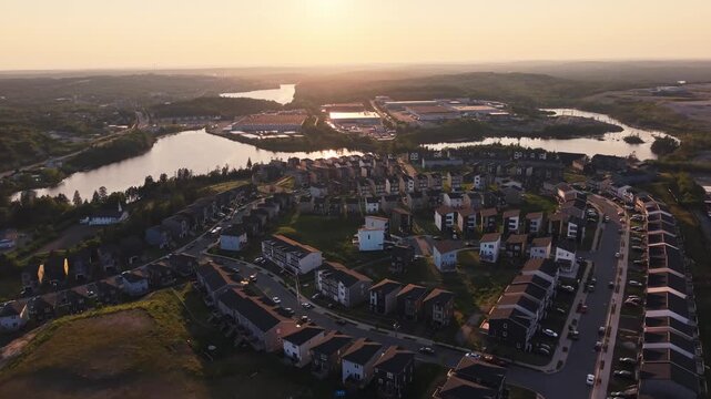 Fire trucks rush through a contemporary community in Halifax, Nova Scotia, bravely responding to an urgent emergency as the sun sets over the horizon