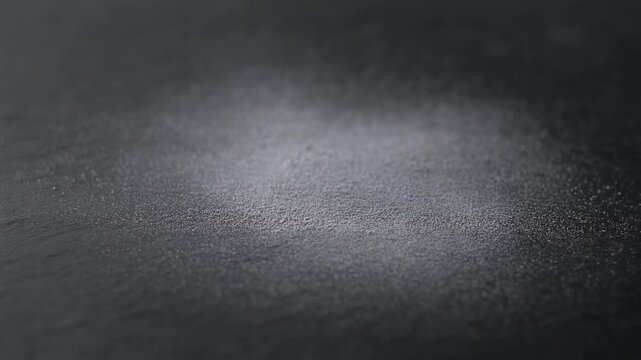 Macro static shot of white chalk dust particles puffing and settling on dark matte slate