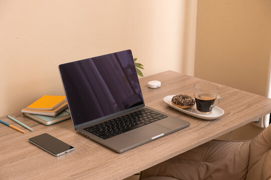Working at a desk with coffee, donuts, and a laptop during the daytime at home