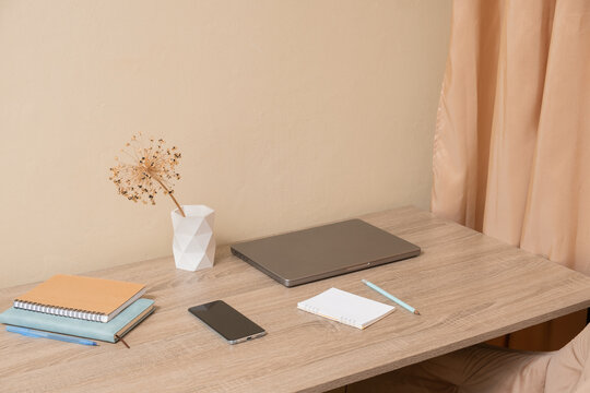 Workspace with laptop, notebook, and phone on wooden table