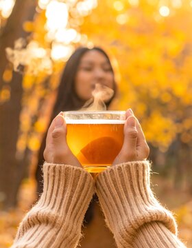 Woman Holding Warm Drink in Autumn Forest