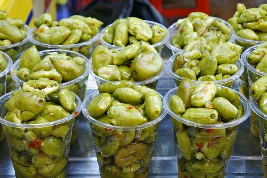 Appetizing street food snack of sweet and sour pickled canarium fruit, ca na chua ngot.