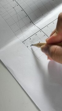 Student plotting points on a mathematical function graph, mathematics lesson, coordinate plane, geometry and education concept.